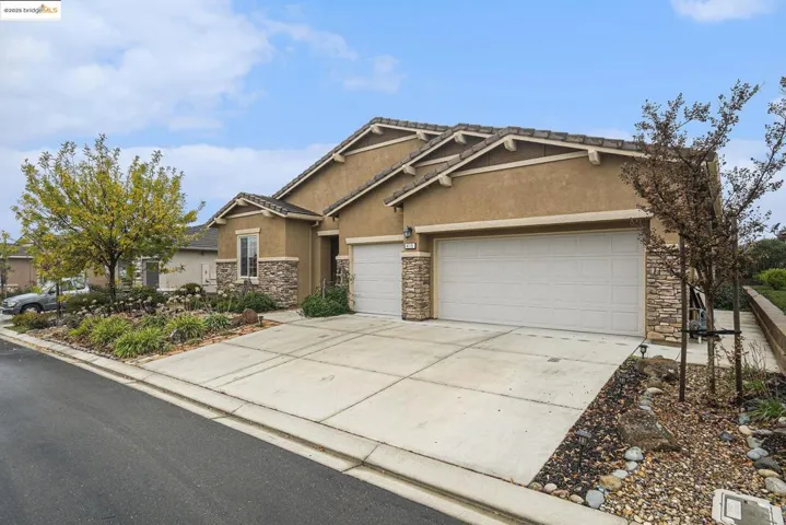 Craftsman-style house with stone siding, stucco siding, driveway, and a garage