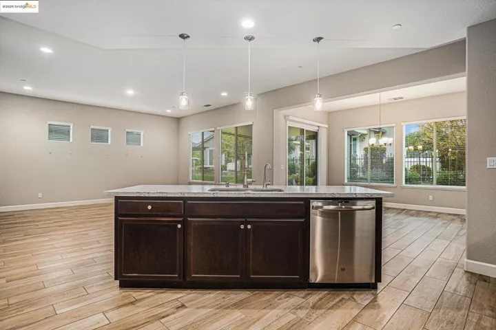Kitchen featuring decorative light fixtures, dishwasher, dark brown cabinetry, wood tiled floors, and recessed lighting