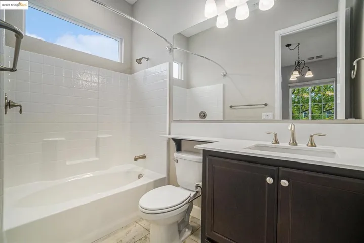 Bathroom with plenty of natural light, shower / bathtub combination, vanity, and light tile patterned floors