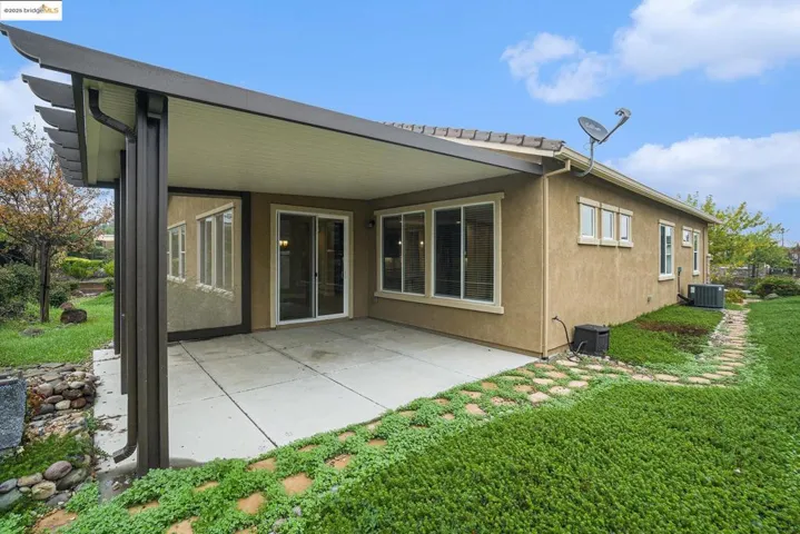 Rear view of house featuring a patio, a yard, and stucco siding