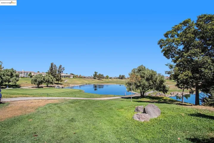 View of property's community featuring a water view, a lawn, and golf course view