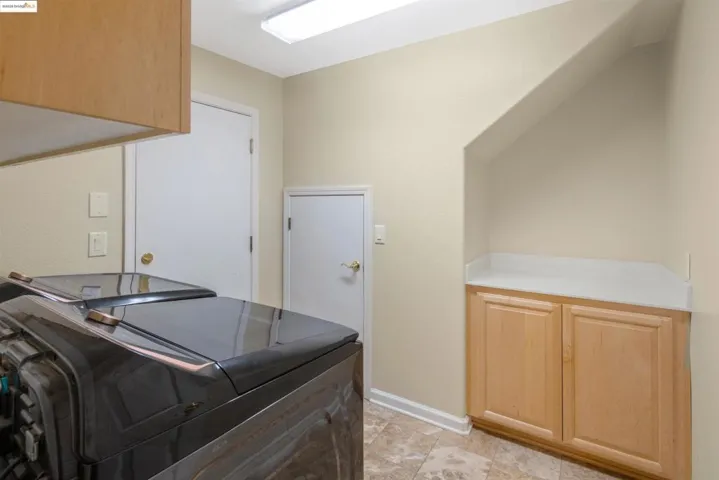 Laundry room featuring cabinet space, washer and dryer, and light tile patterned flooring