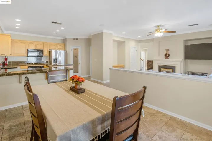 Dining room featuring ornamental molding, recessed lighting, a fireplace, light tile patterned flooring, and ceiling fan