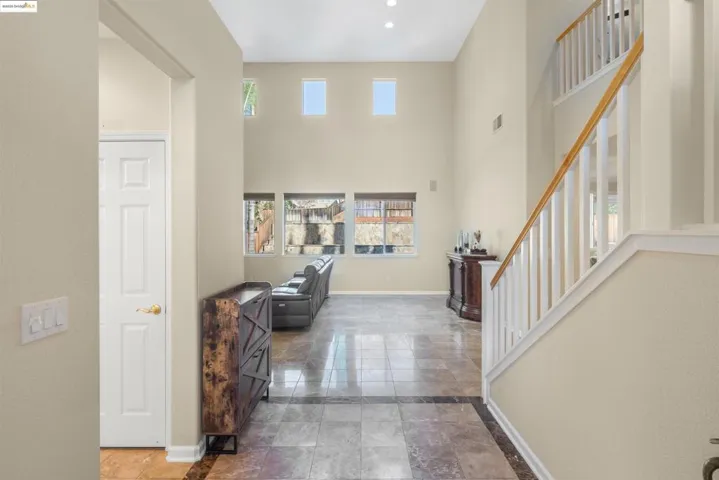 Entryway featuring plenty of natural light, inlaid floor details, stairs, and a towering ceiling