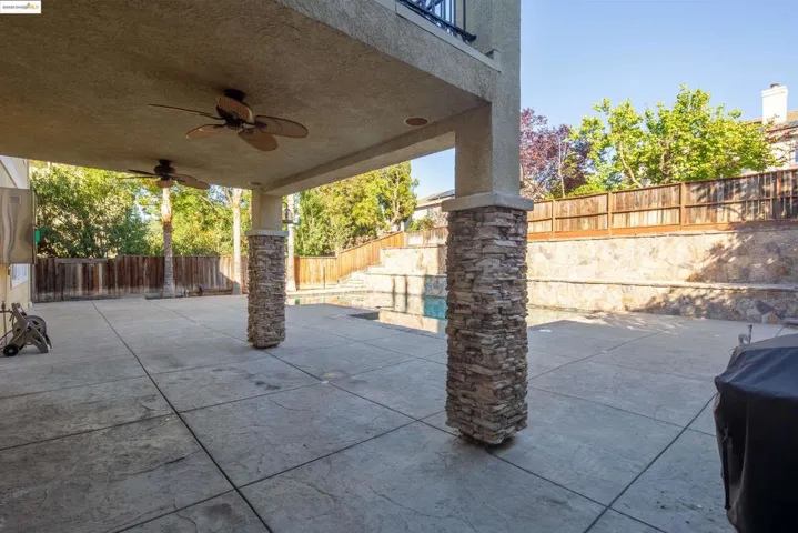Fenced backyard featuring a patio area and a ceiling fan