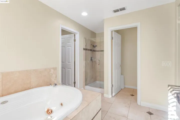 Full bath featuring a whirlpool tub, light tile patterned flooring, a shower stall, and recessed lighting