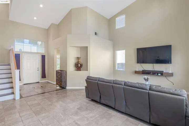 Living area with a high ceiling, healthy amount of natural light, stairs, and recessed lighting