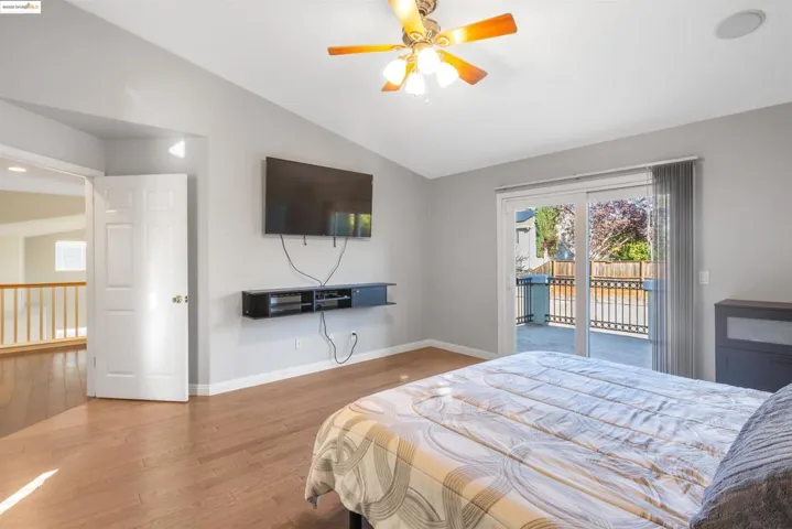 Bedroom featuring lofted ceiling, wood finished floors, access to outside, and a ceiling fan