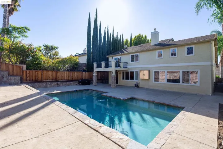 View of pool featuring a patio, a fenced backyard, and a balcony