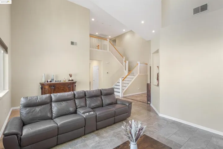 Living room with a towering ceiling, stairway, and recessed lighting