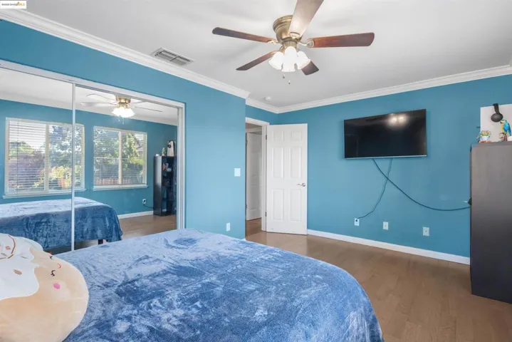 Bedroom featuring wood finished floors, ceiling fan, a closet, and crown molding