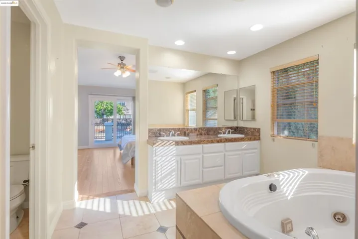 Bathroom featuring ensuite bath, double vanity, light tile patterned floors, a garden tub, and recessed lighting