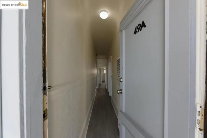 Hallway featuring dark wood-style floors and a wainscoted wall