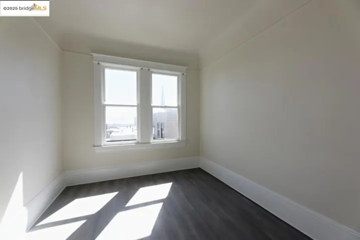 Empty room with dark wood-style flooring and baseboards