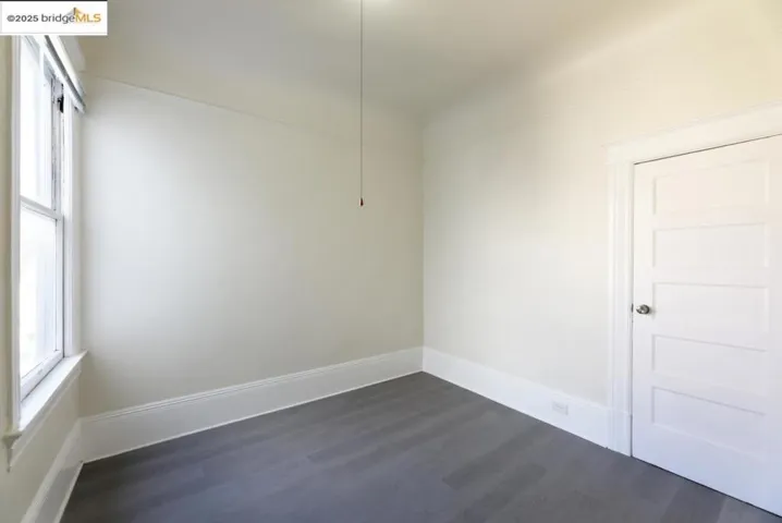 Unfurnished room with dark wood finished floors and baseboards