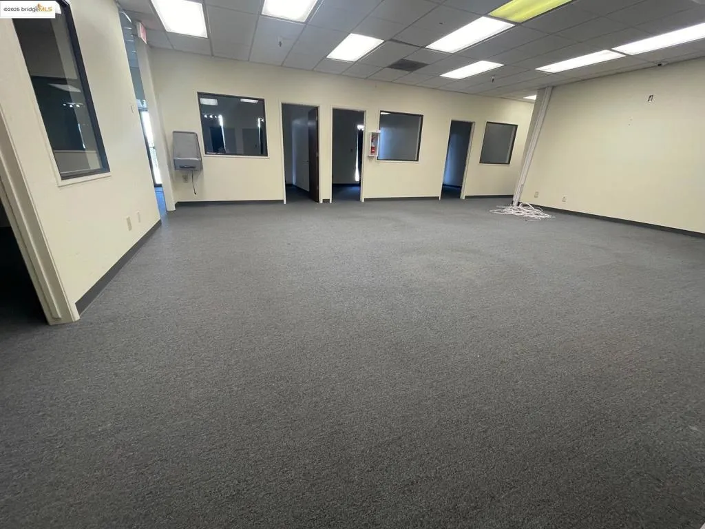 Unfurnished room featuring dark colored carpet and a drop ceiling