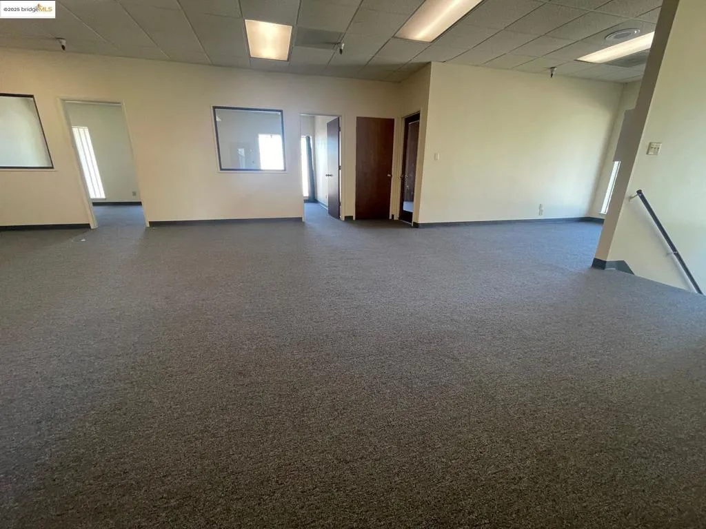 Carpeted spare room featuring a paneled ceiling and baseboards
