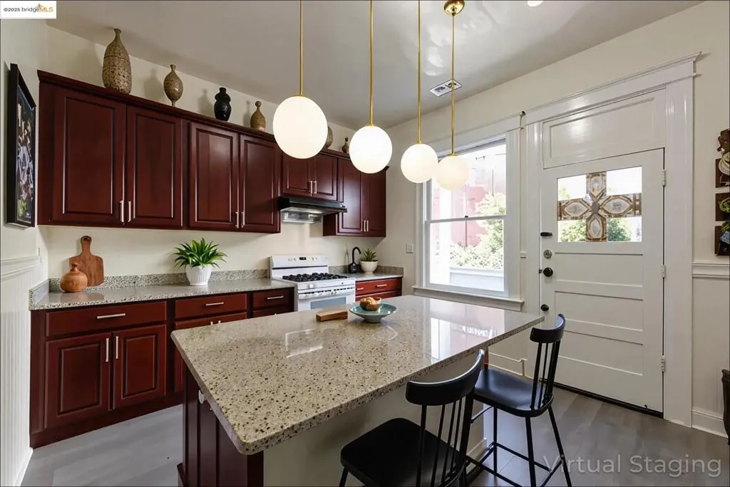 Virtually Stage Kitchen with light stone counters, decorative light fixtures, a kitchen bar, white range with gas stovetop, and a kitchen island
