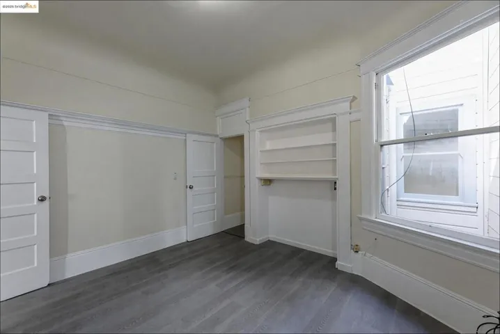 Unfurnished living room with dark wood-type flooring and a closet