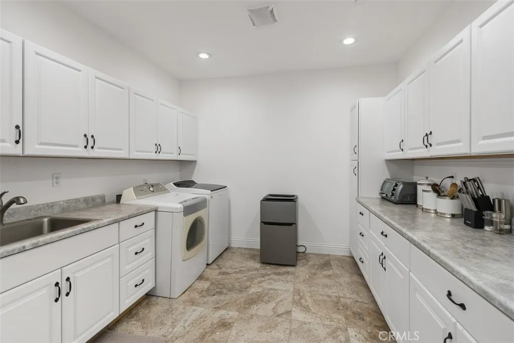 spacious upstairs laundry room with sink and loads of cabinetry