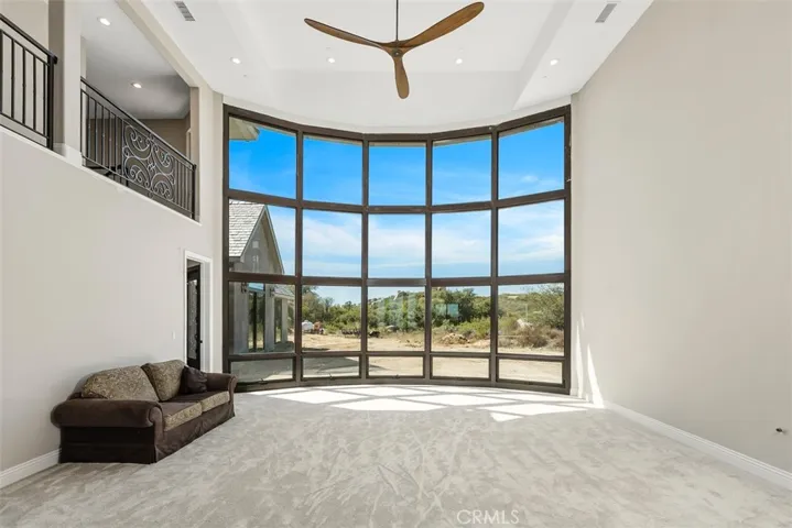 Formal living room with floor to ceiling windows, ceiling fan and propane line for future fireplace
