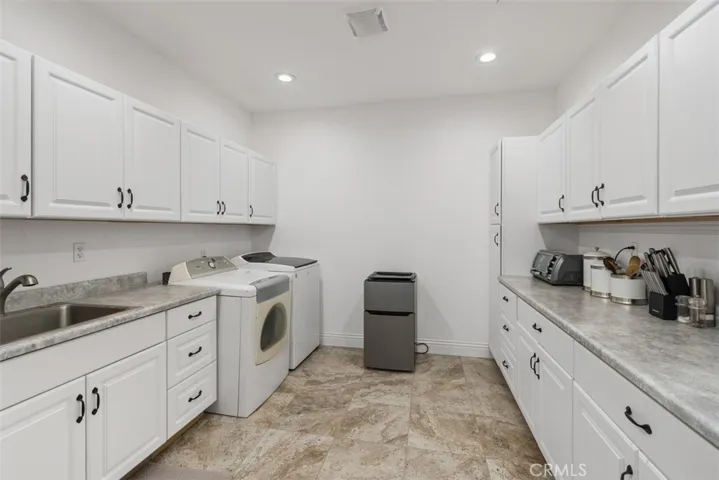 spacious upstairs laundry room with sink and loads of cabinetry