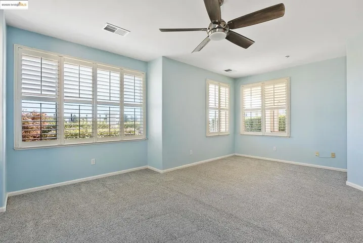 Carpeted empty room featuring baseboards and ceiling fan