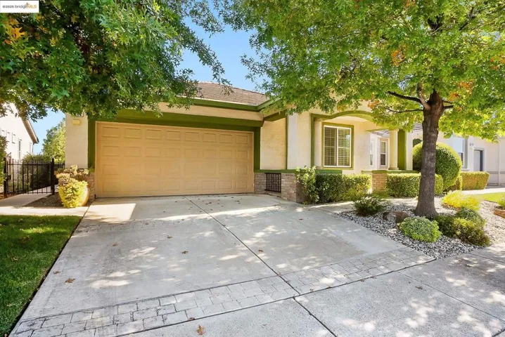 View of front facade with stucco siding, driveway, stone siding, and a garage
