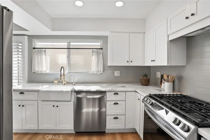 Kitchen with natural stone counters, farm house sink and updated Euro hinge cabinets.