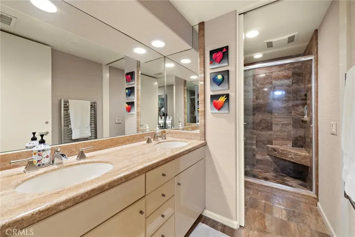 Hall bath shared by the guest bedrooms features dual sinks and lavish walk-in shower.