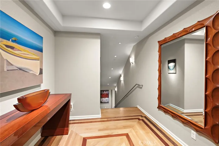 Enter into the foyer with gorgeous wood flooring and art lighting leading you down the stairs.