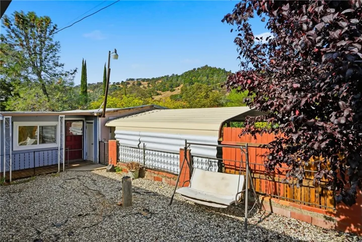 Side yard with office space to the left, covered parking in center and driveway behind the red fence.