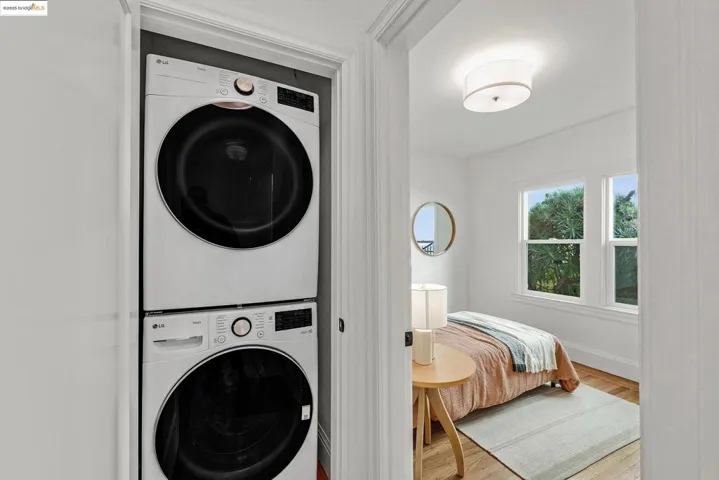 Laundry area featuring wood finished floors and stacked washer / drying machine