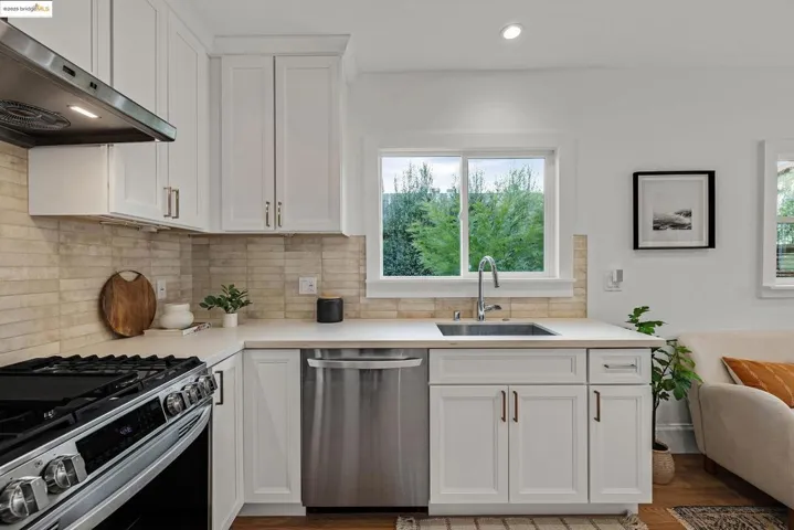 Kitchen with white cabinets, appliances with stainless steel finishes, extractor fan, decorative backsplash, and recessed lighting