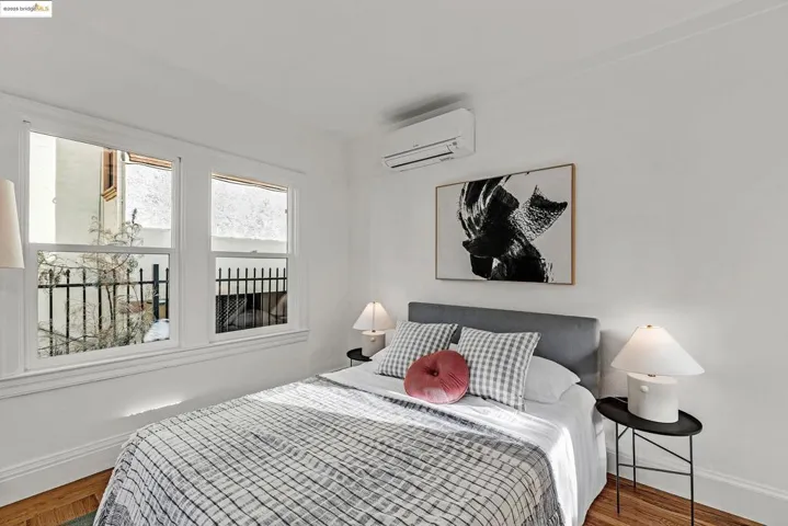 Bedroom with wood finished floors and an AC wall unit