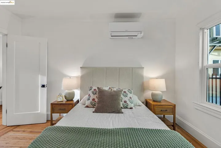 Bedroom with wood finished floors and an AC wall unit