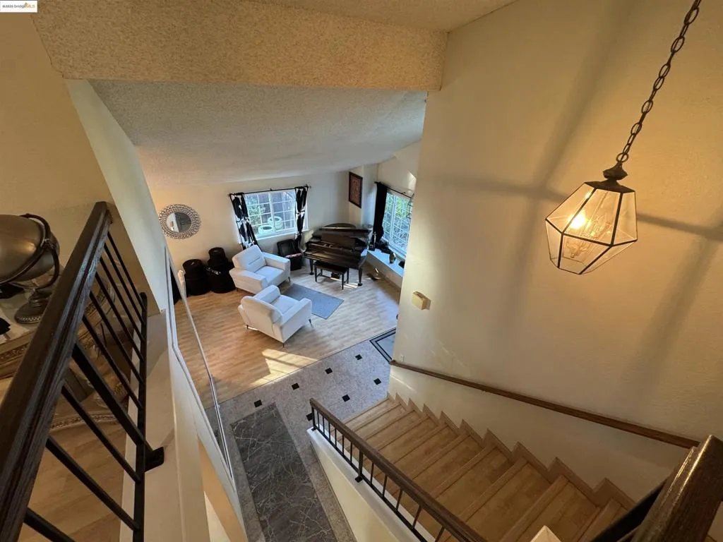 Staircase with a textured ceiling, vaulted ceiling, and wood finished floors