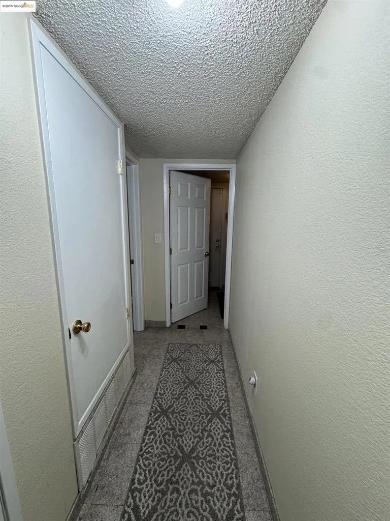 Hall featuring a textured ceiling and a textured wall