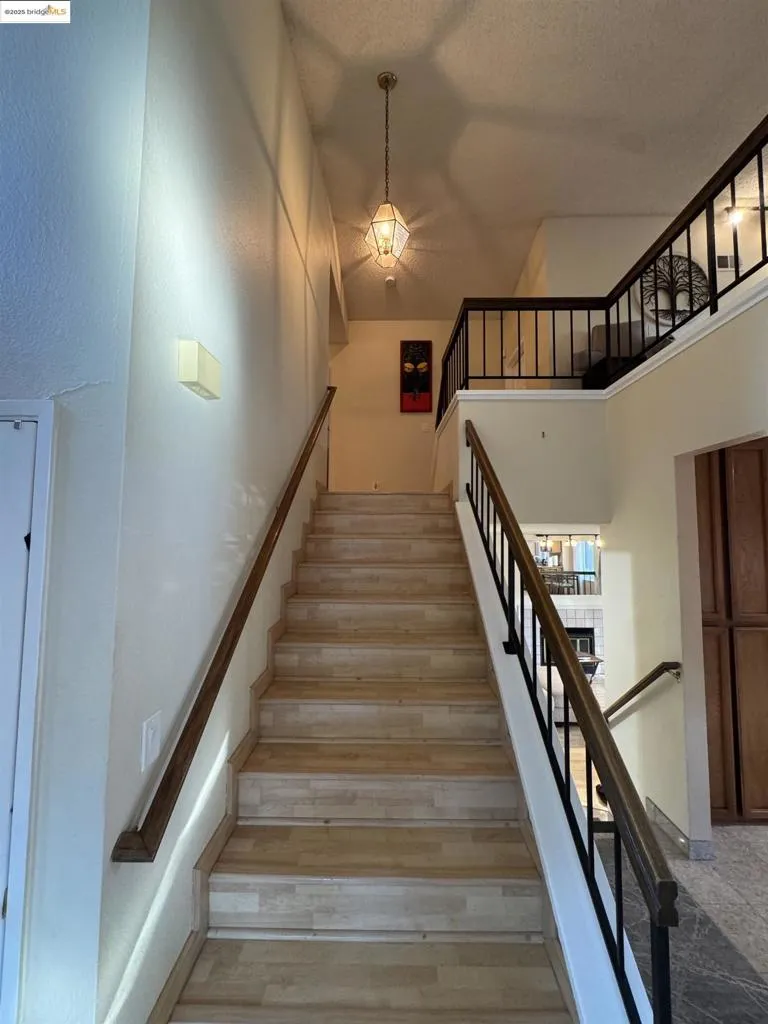 Stairs featuring wood finished floors, a towering ceiling, and a textured ceiling