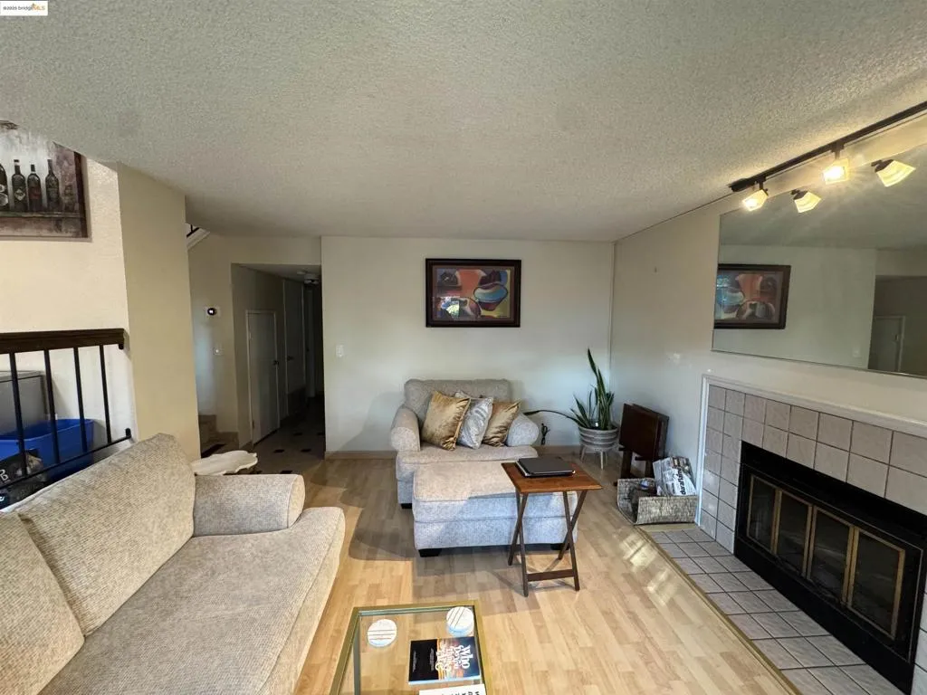 Living room featuring a fireplace, rail lighting, wood finished floors, and a textured ceiling