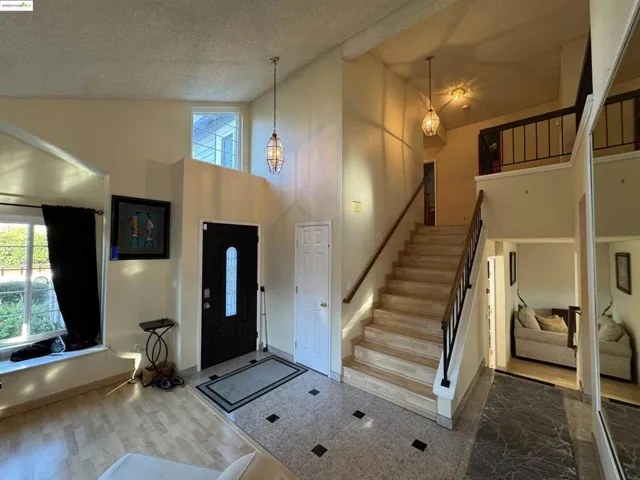 Foyer with high vaulted ceiling, stairway, a textured ceiling, and wood finished floors