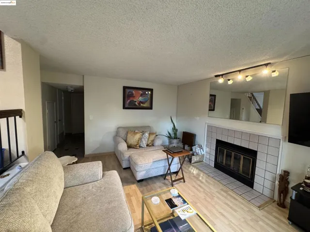 Living area featuring a fireplace, wood finished floors, a textured ceiling, and track lighting