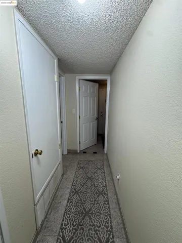 Hall featuring a textured ceiling and a textured wall