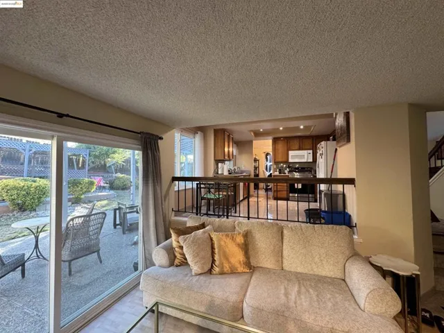 Living area featuring stairway, a textured ceiling, and light wood-style floors