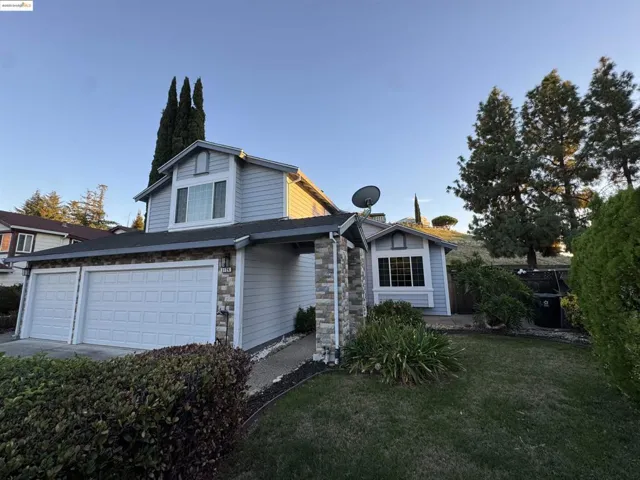 View of front of home with stone siding, a garage, and a front yard