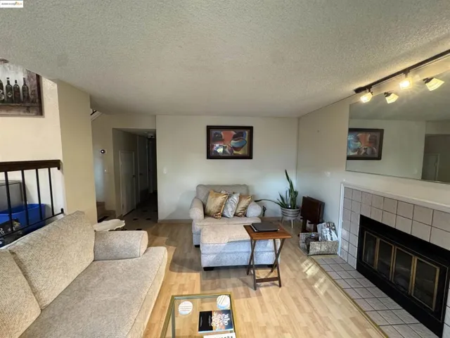 Living room featuring a fireplace, rail lighting, wood finished floors, and a textured ceiling