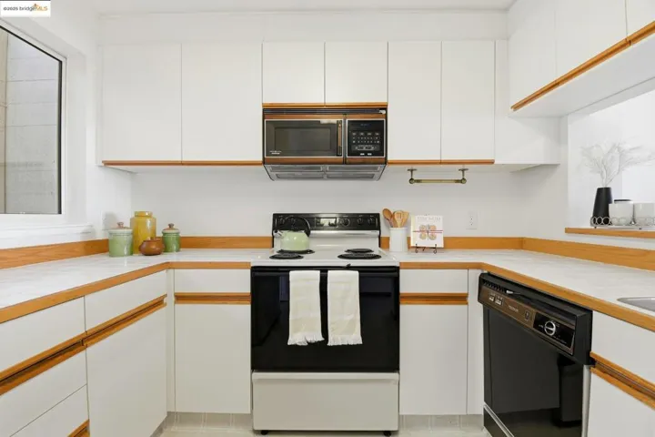 Kitchen featuring white cabinetry, electric stove, and dishwasher