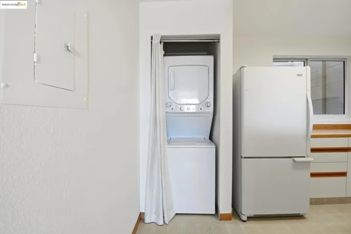 Washroom with stacked washing machine and dryer and baseboards