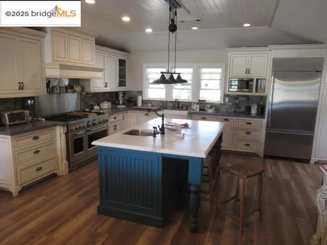 Kitchen featuring recessed lighting, built in appliances, tasteful backsplash, dark wood-type flooring, and hanging light fixtures