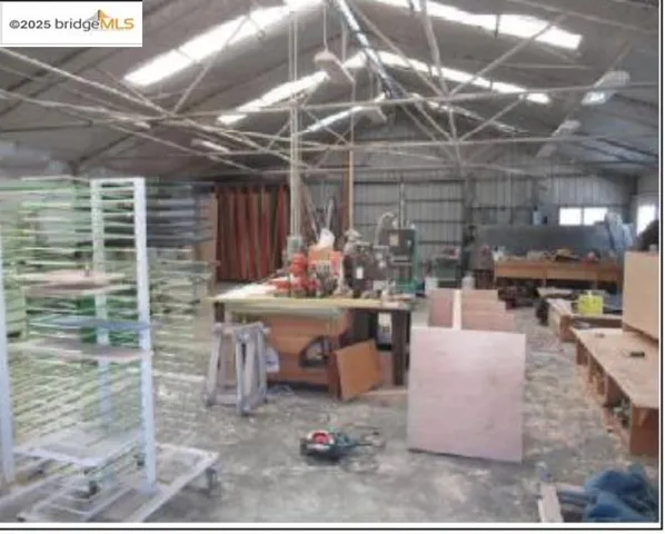Miscellaneous room with unfinished concrete floors, a workshop area, and lofted ceiling